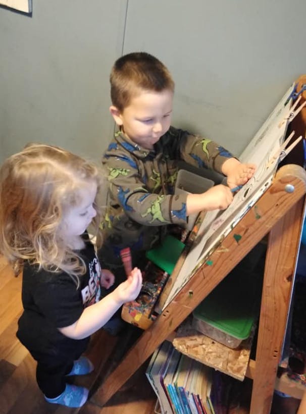 Two children playing with an easel