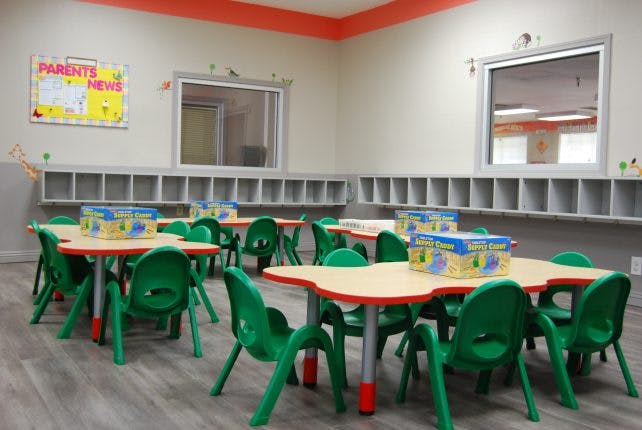 Empty classroom with small tables and green chairs