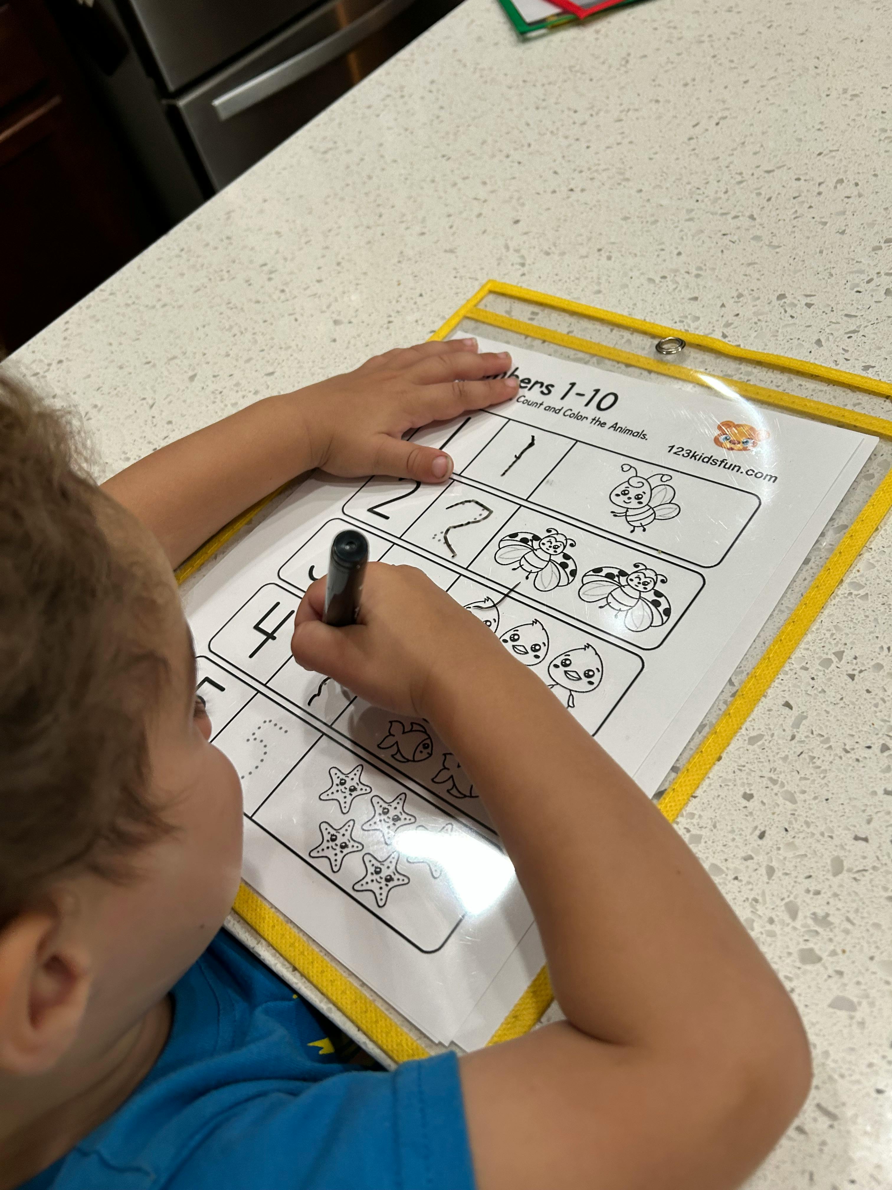 Child writing numbers on a worksheet with a marker