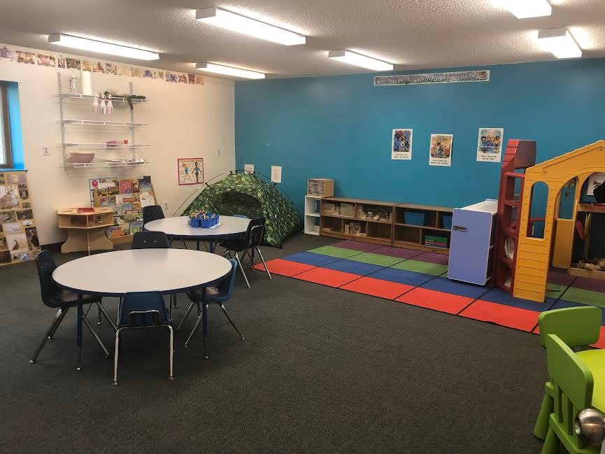 Playroom with tables, chairs, and play structures