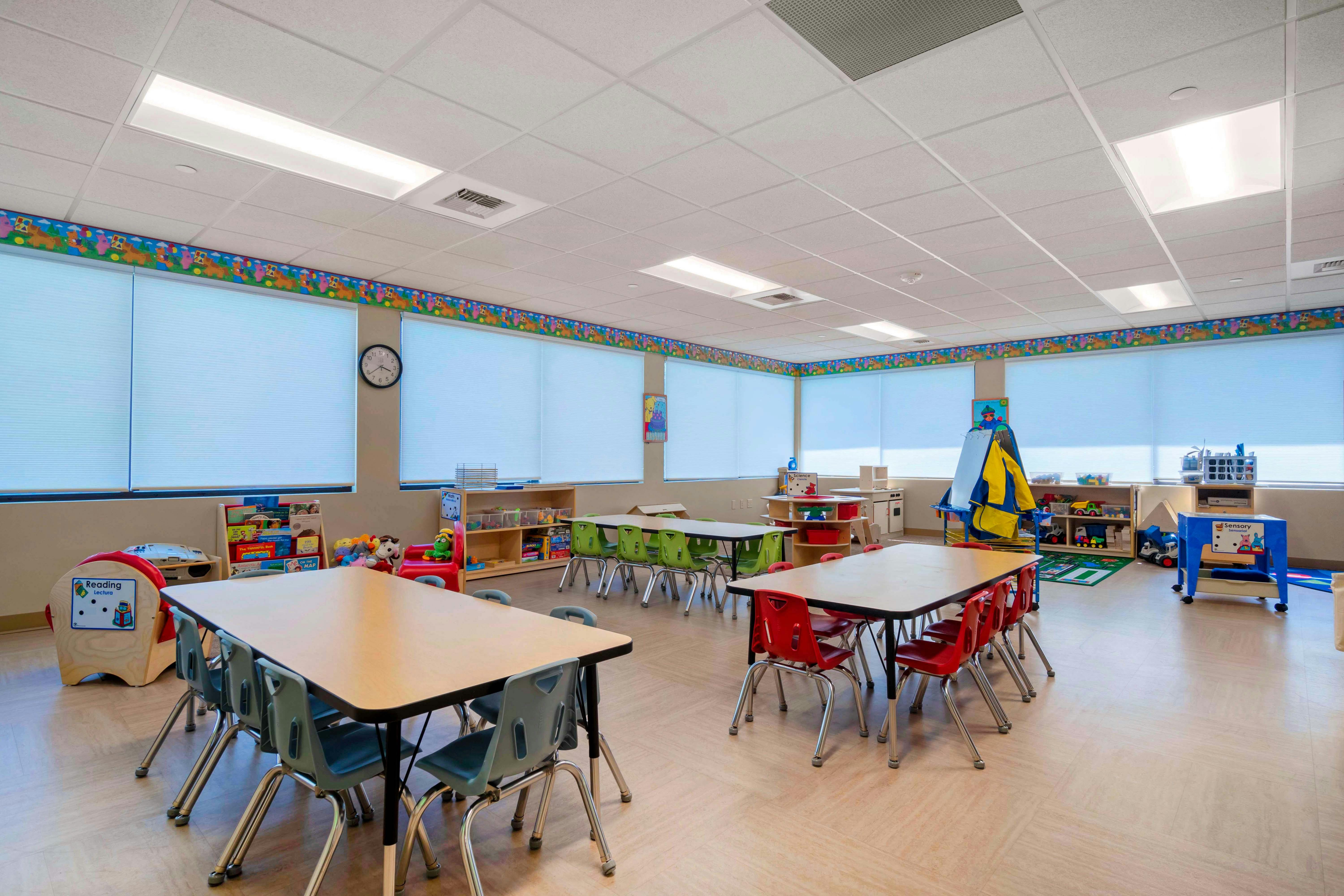 Empty colorful preschool classroom with tables, chairs, and toys