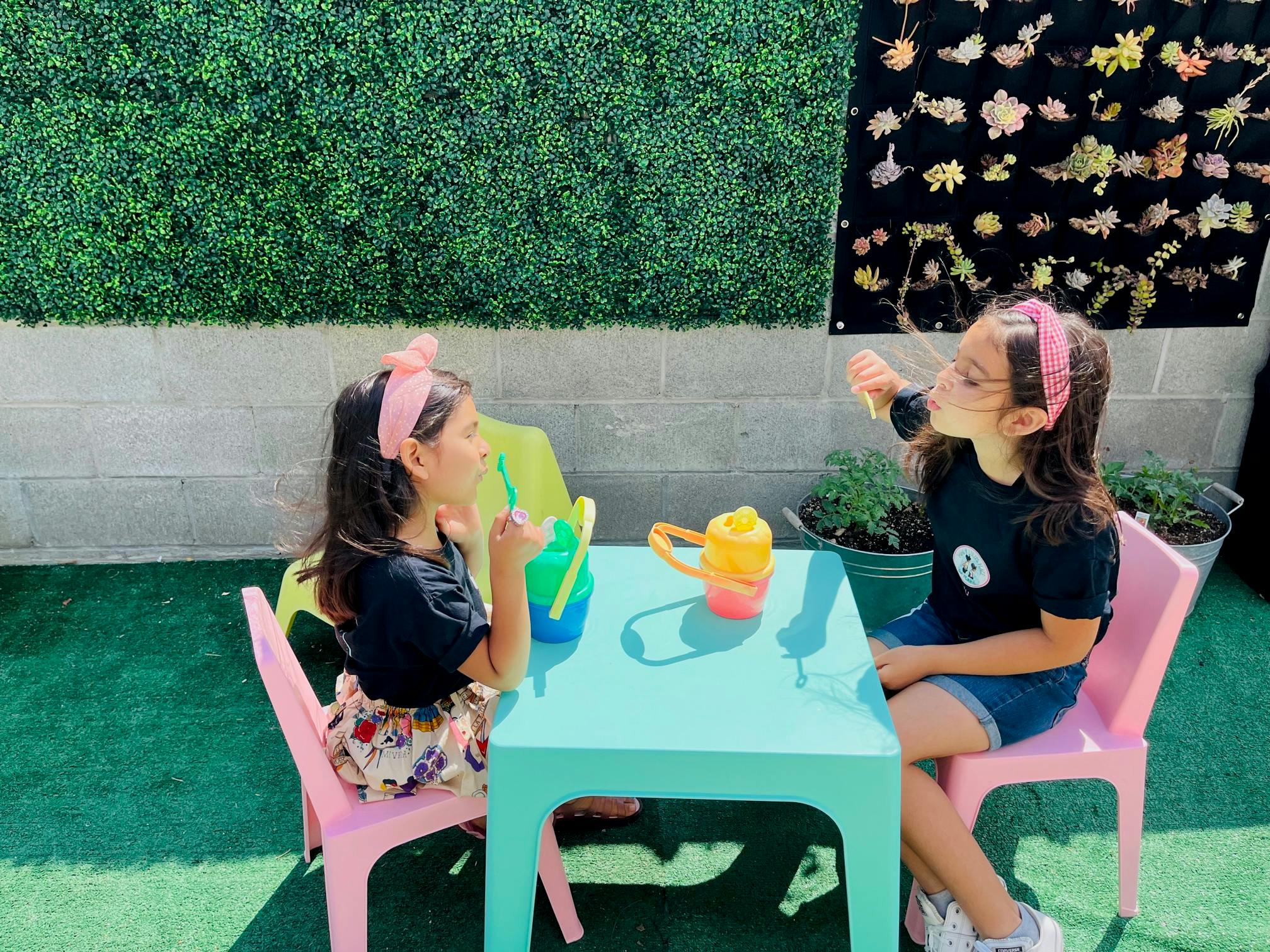 Two children sitting at a small table with toys