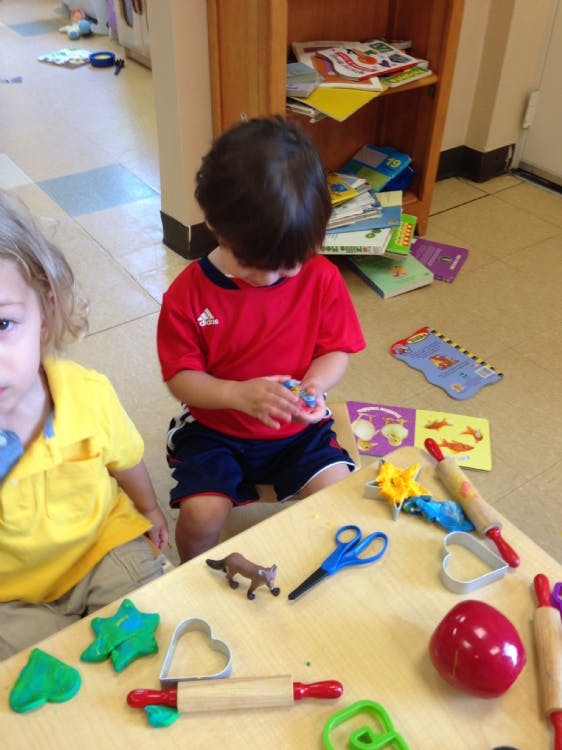 Child playing with modeling clay and cookie cutters at a table