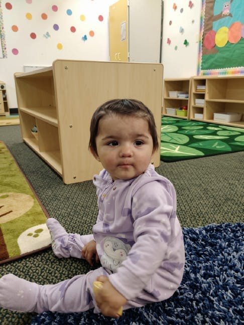 A small child sitting on a rug in a classroom
