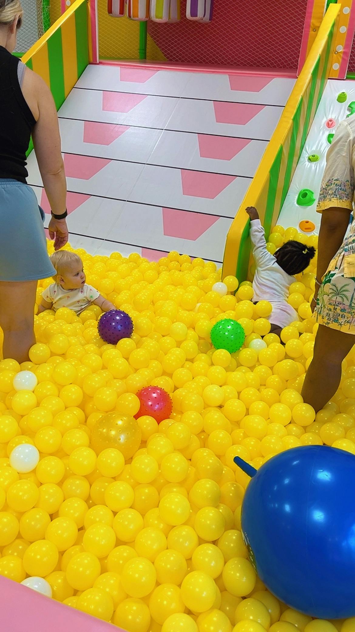 People and children in a yellow ball pit