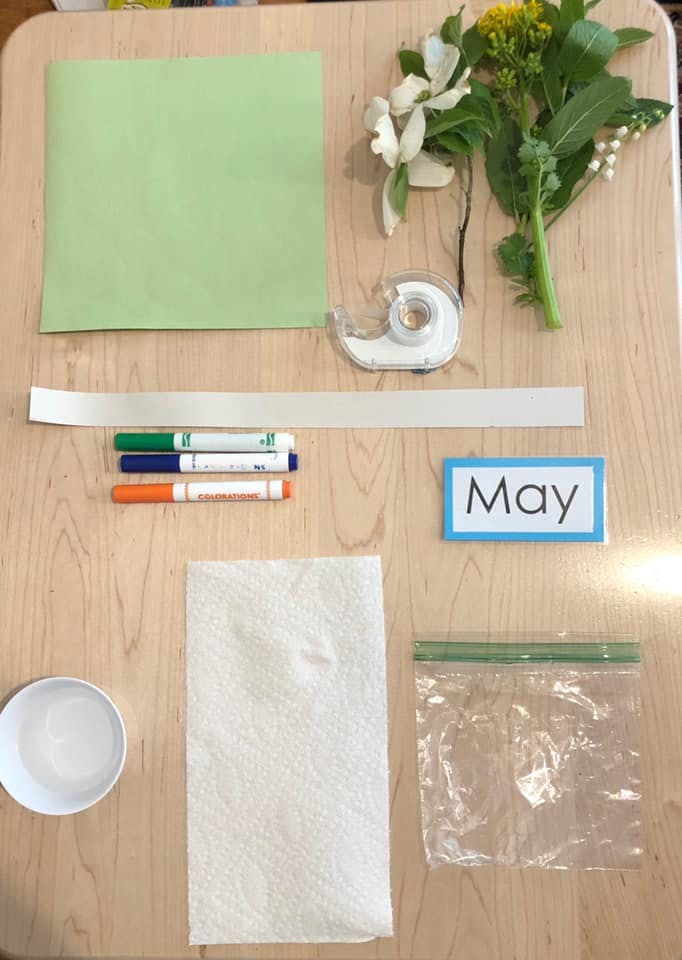 Craft supplies including paper, markers, tape, flowers, and a sign that says May