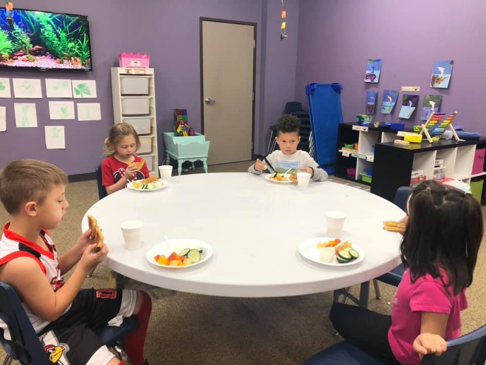 Four children eating at a round table in a room