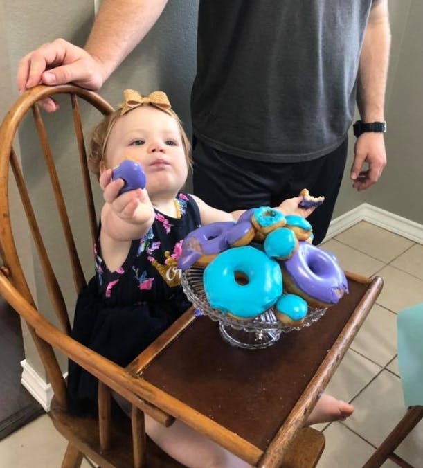 Child in a high chair with a platter of blue and purple donuts