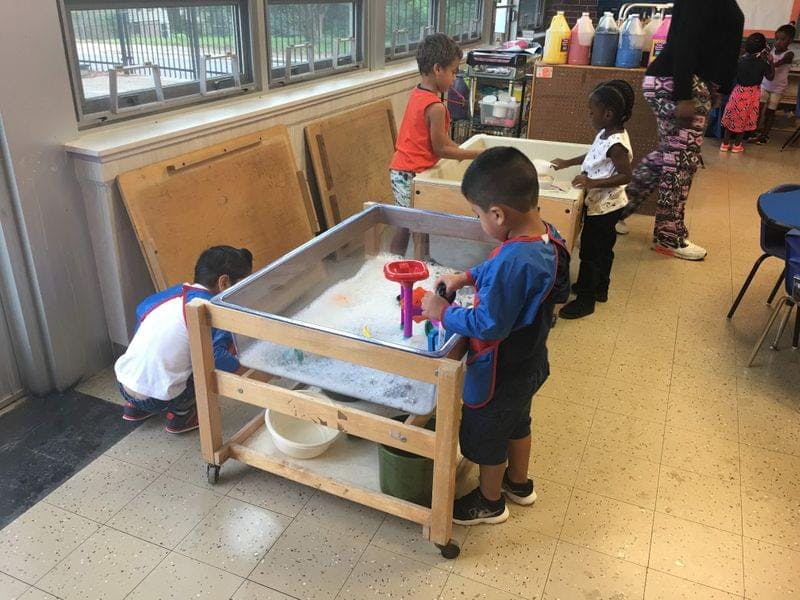 Children playing at a sand and water table in a classroom
