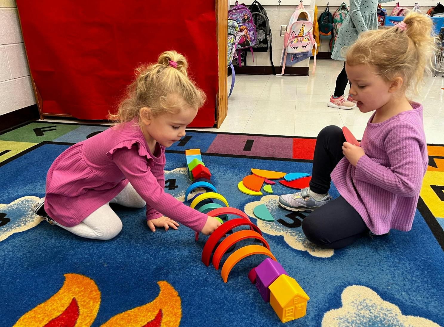 Two children playing with colorful blocks on a blue rug