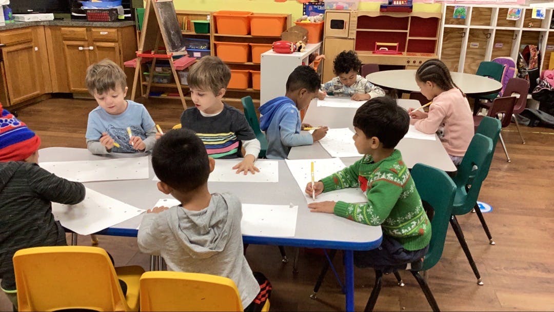 Children drawing at tables in a classroom