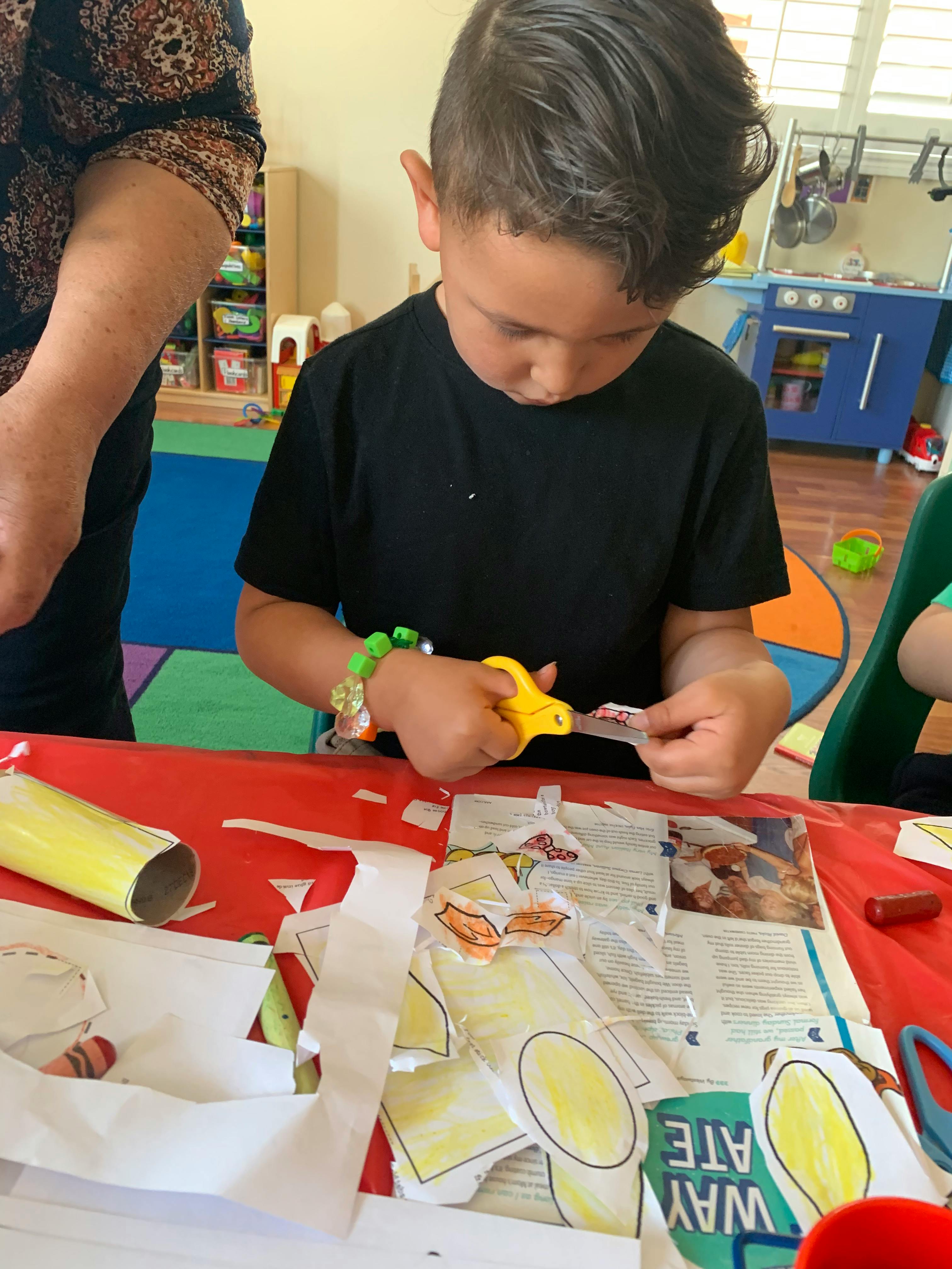 Child cutting paper with scissors at a table