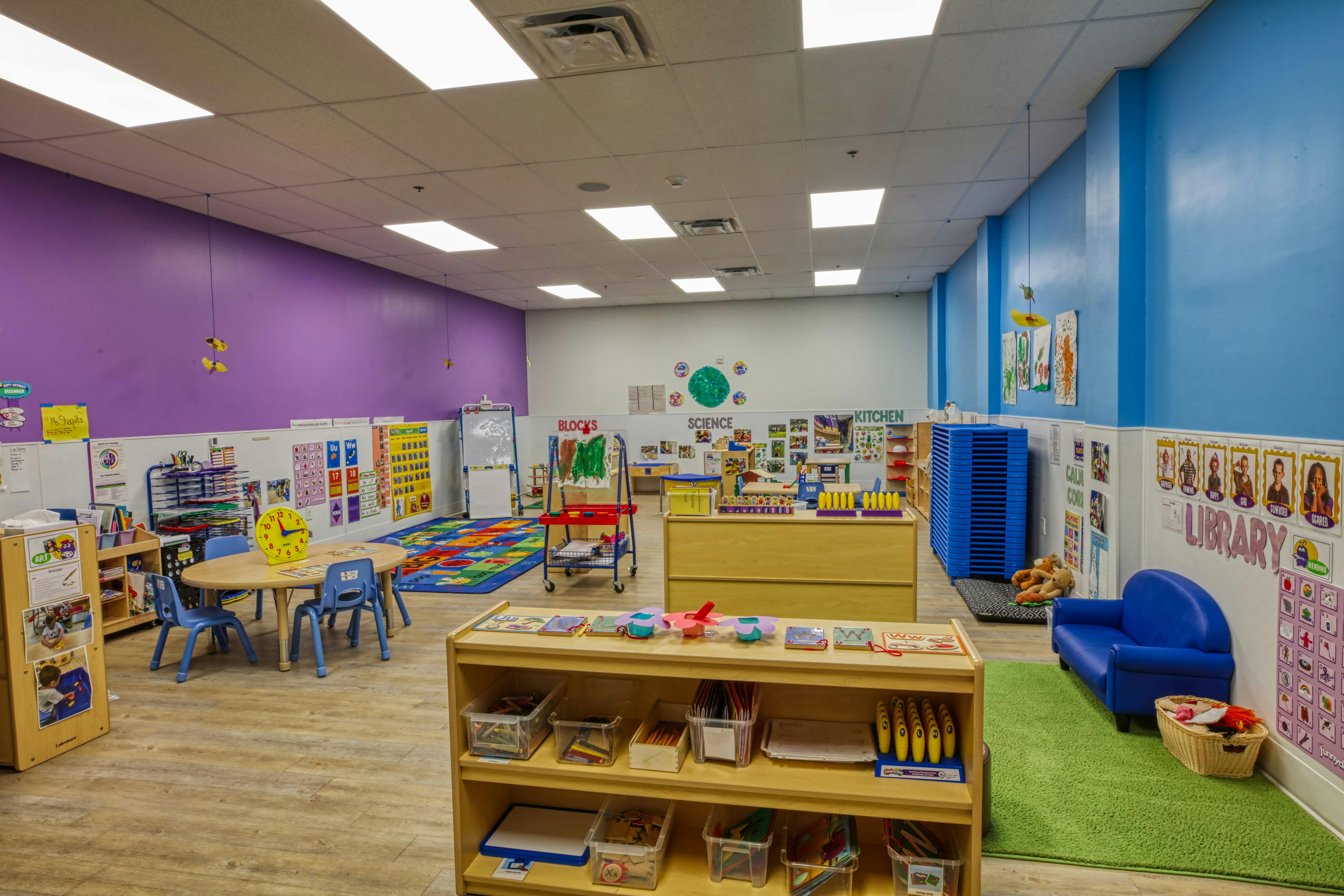 Colorful classroom with various learning stations, tables, and play areas
