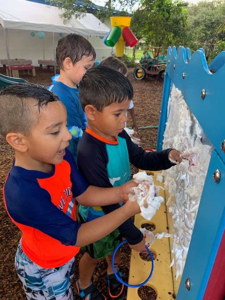 Two children playing with foam on a blue and yellow activity board