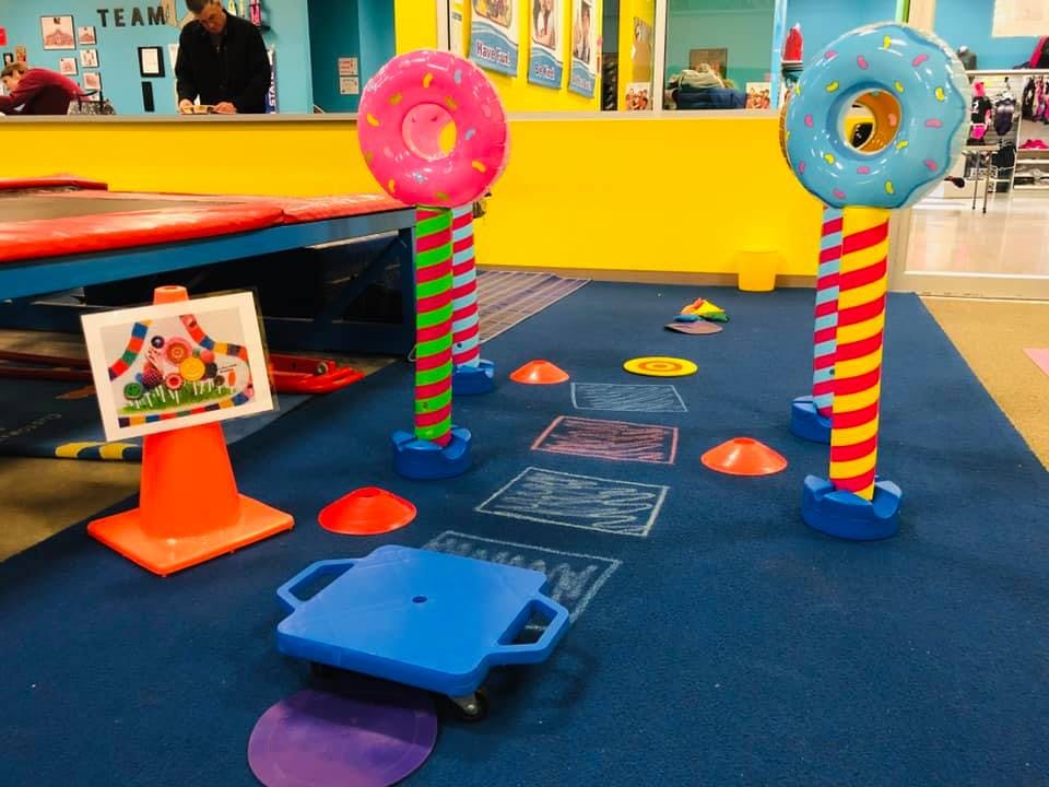 Indoor play area with colorful donut-shaped poles and floor markings