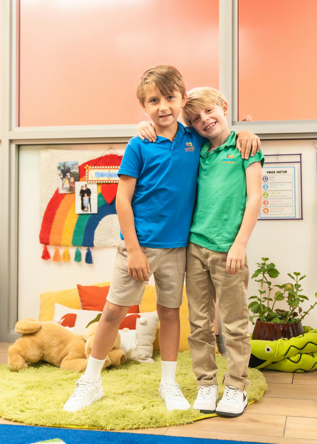Two children standing with arms around each other in a classroom