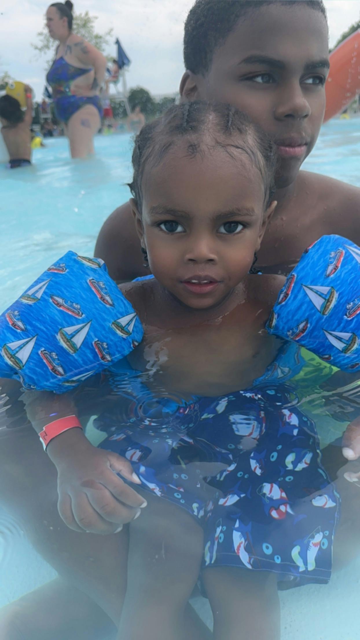 Child in arm floaties in water with teen