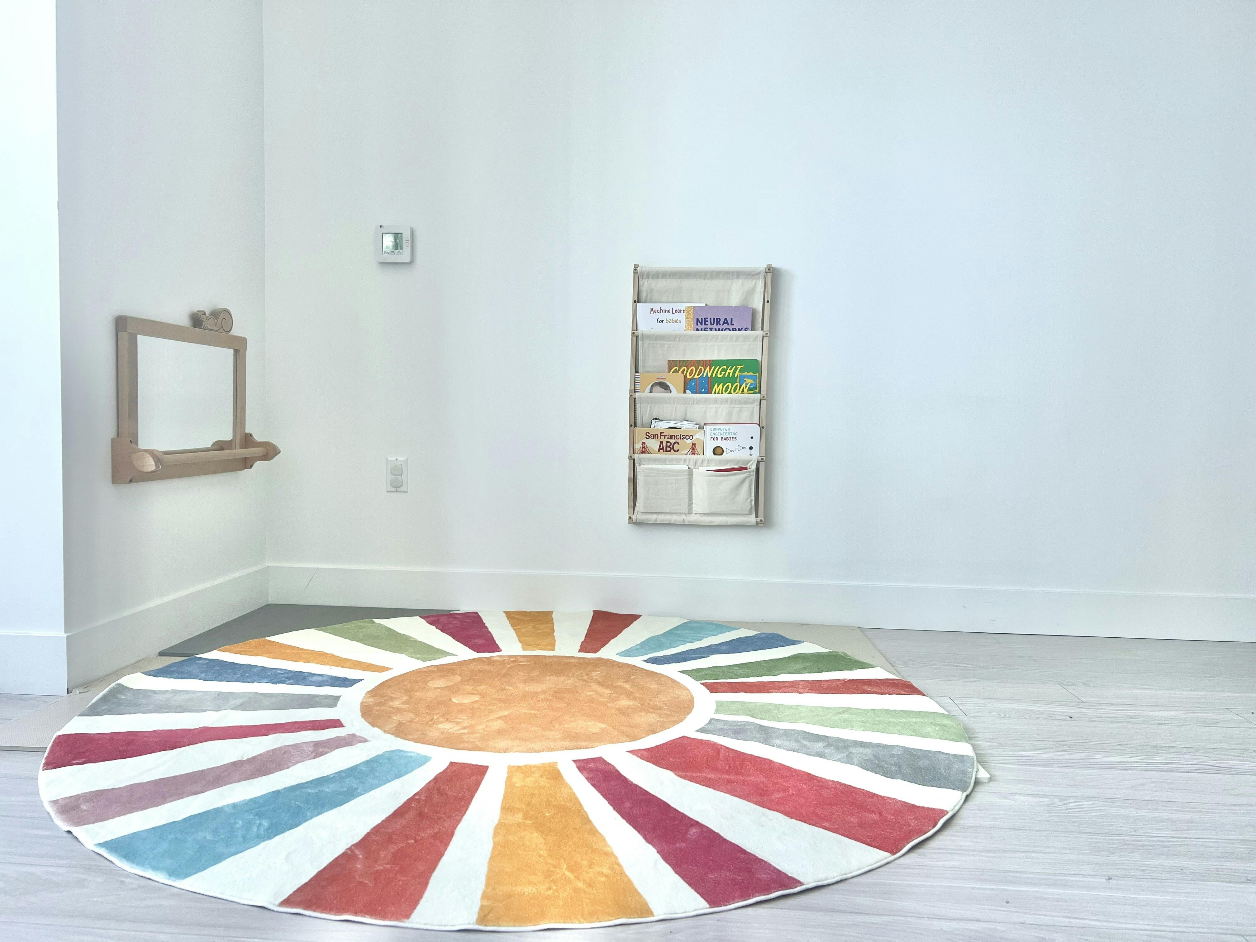 Colorful sunburst rug on a light floor with a wall-mounted bookshelf
