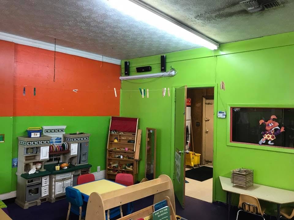 Playroom with green and orange walls, toy kitchen, and small tables