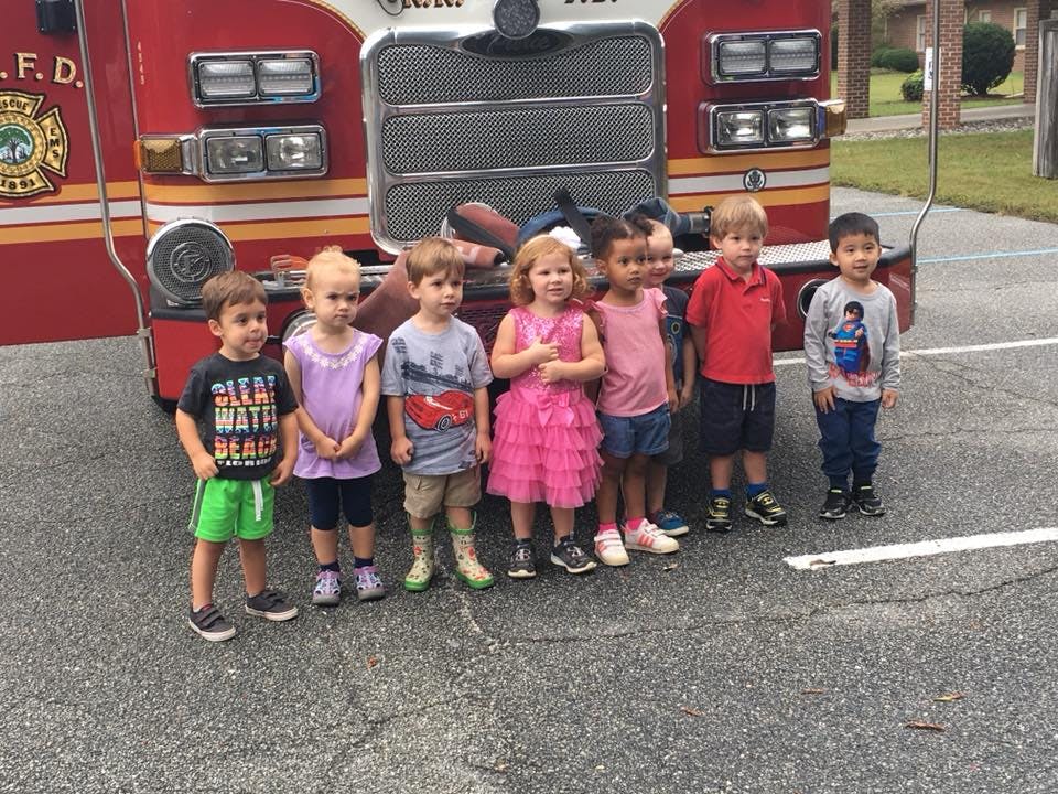 Group of children standing in front of a fire truck