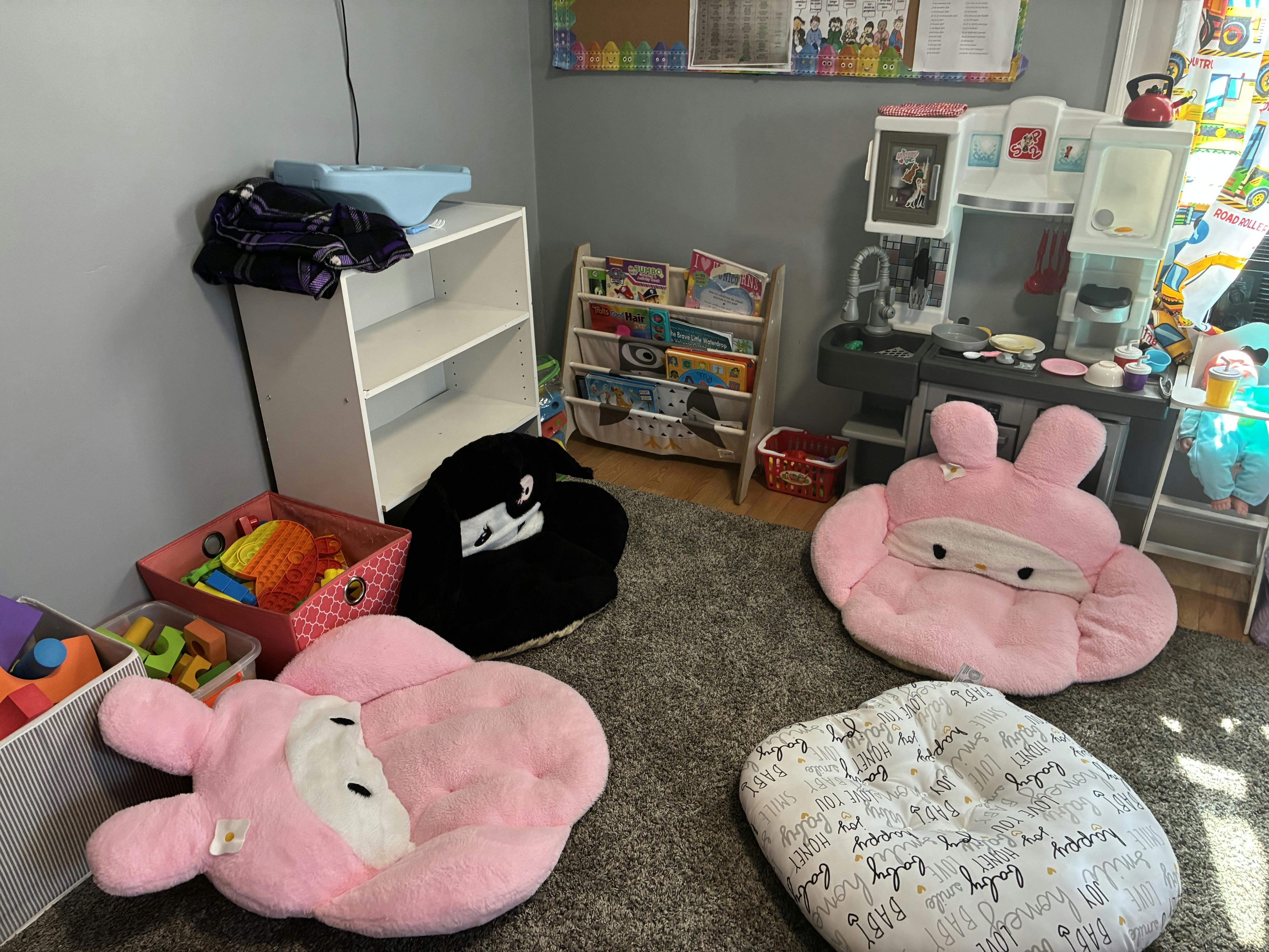 Playroom with character-themed floor cushions and a toy kitchen