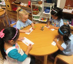 Four children drawing at a round table