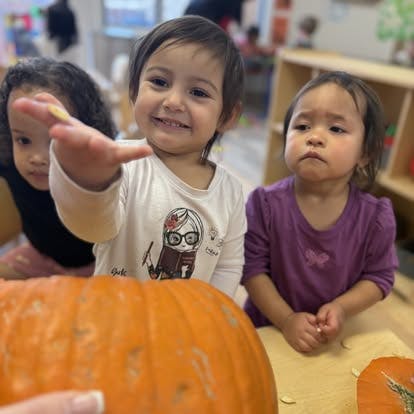 Three children looking at a pumpkin