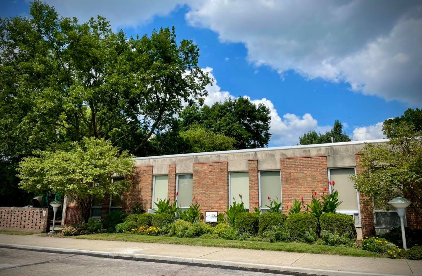 Brick building with windows and landscaping under a cloudy sky