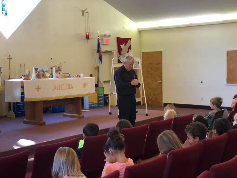 Adult speaking to children in a room with an altar