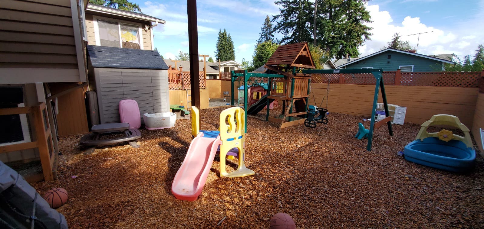 Backyard playground with slide and swing set on wood chips