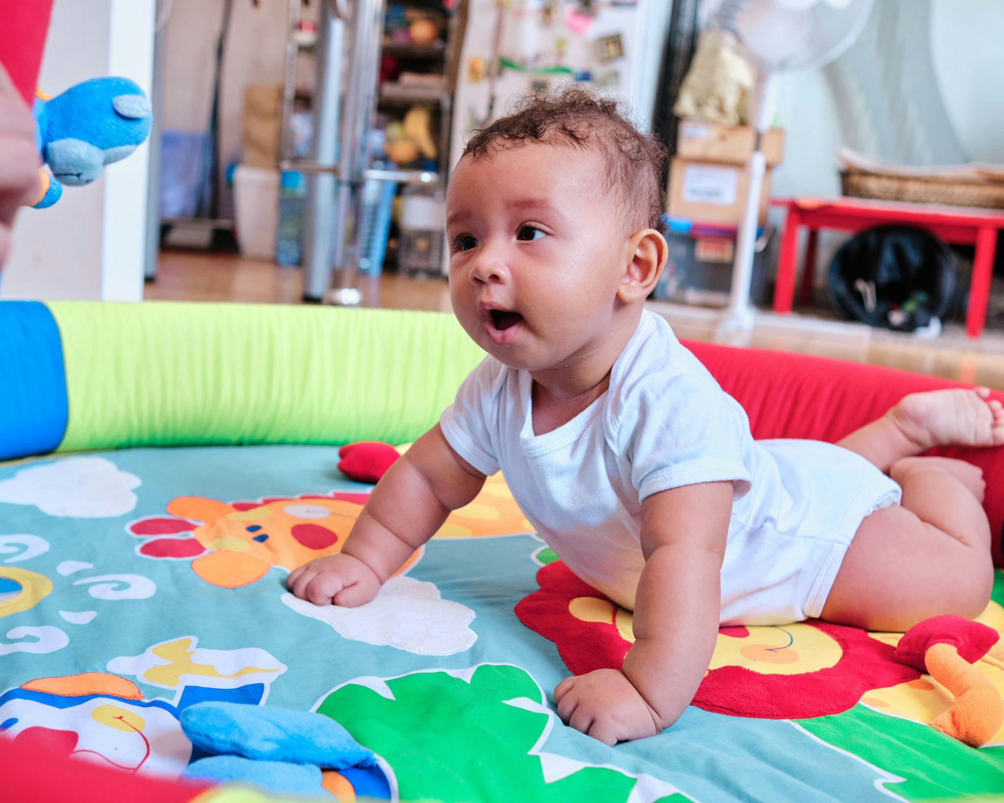Child on a playmat looking at a toy