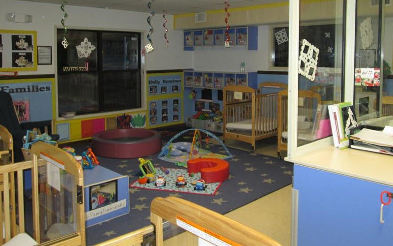 An empty play area with several cribs, toys, and decorations