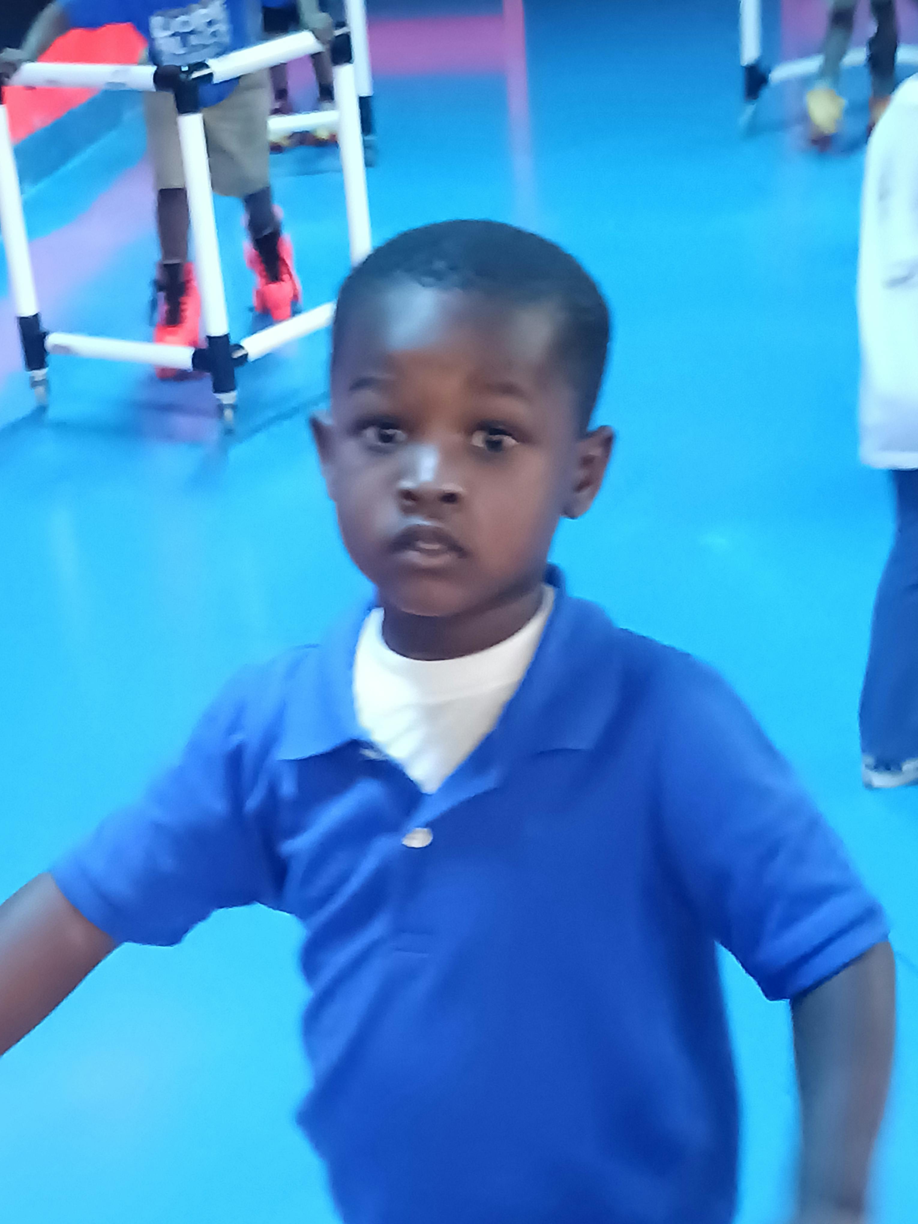 Child in a blue polo shirt looking forward