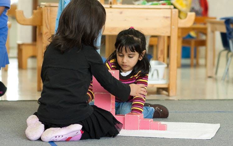 Two children playing with pink blocks on the floor