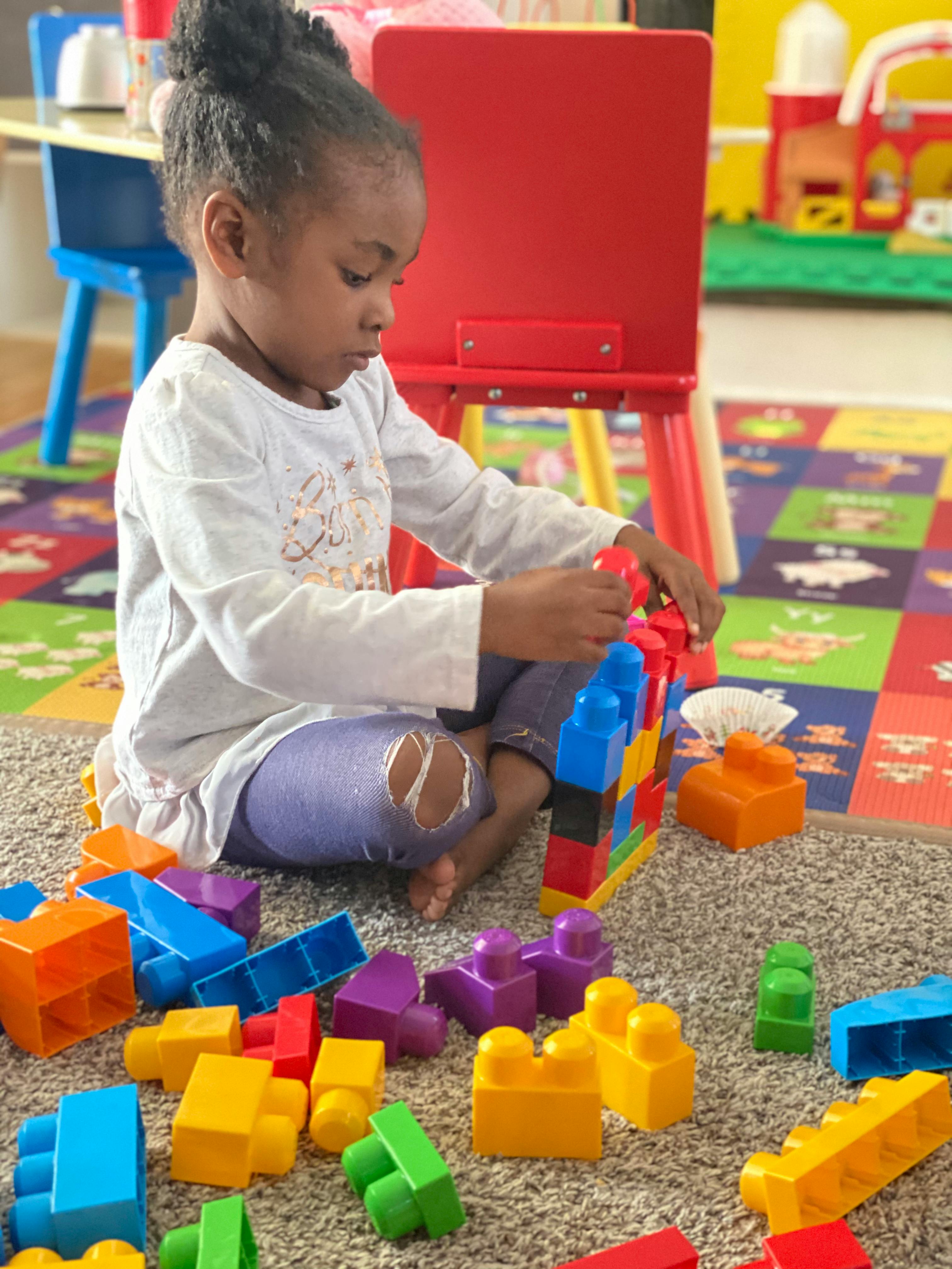 Child playing with colorful building blocks on a rug