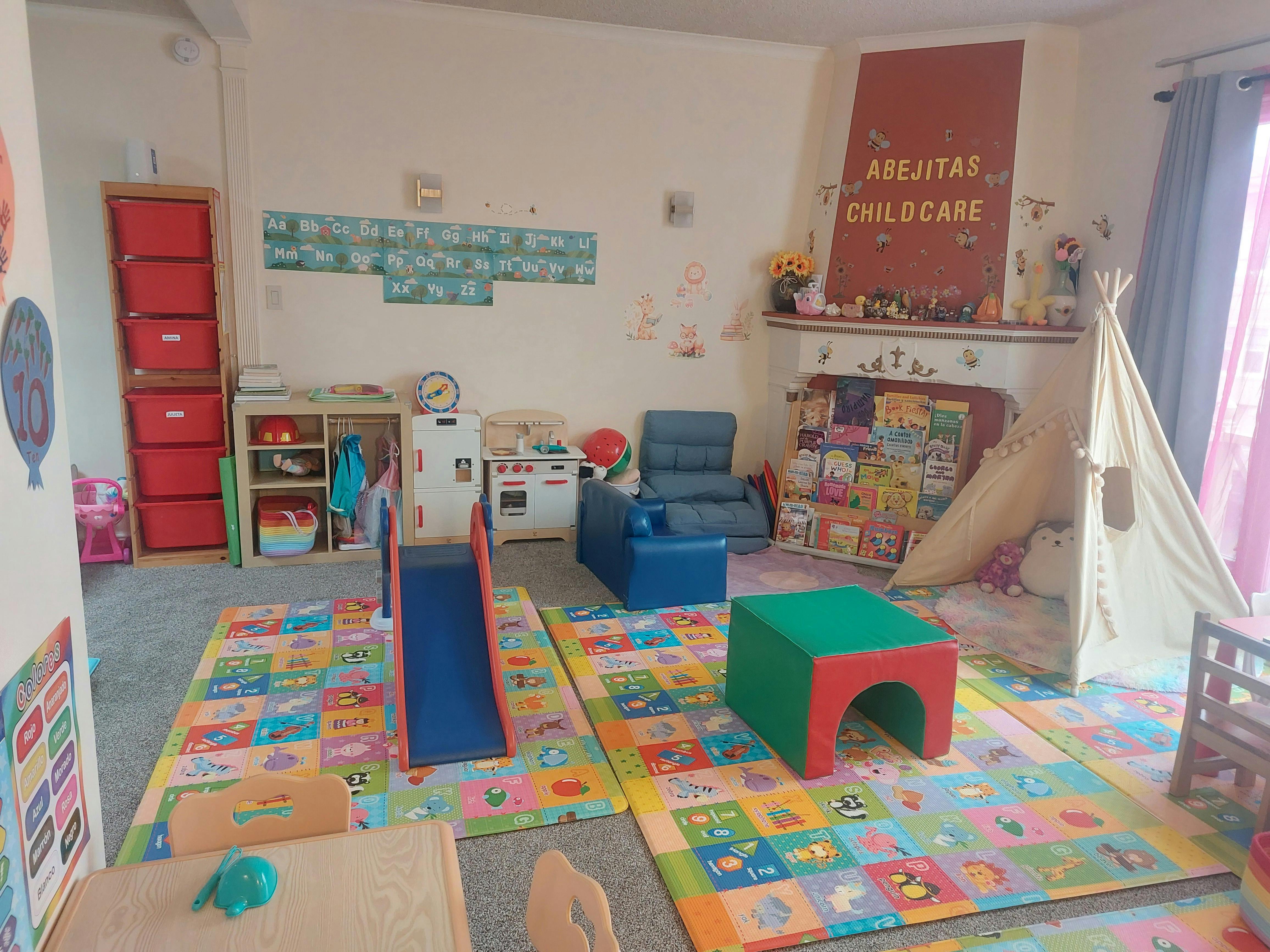 Childcare room with play mats, slide, and sign reading "Abejitas Childcare"