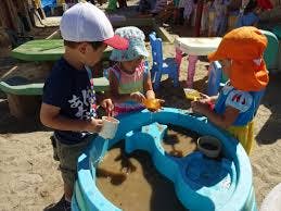 Three children playing in a sand and water table