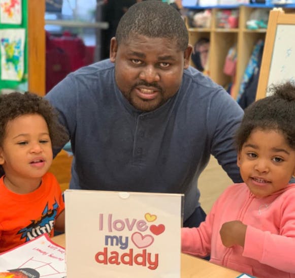 Person with two children and a sign that says "I love my daddy"