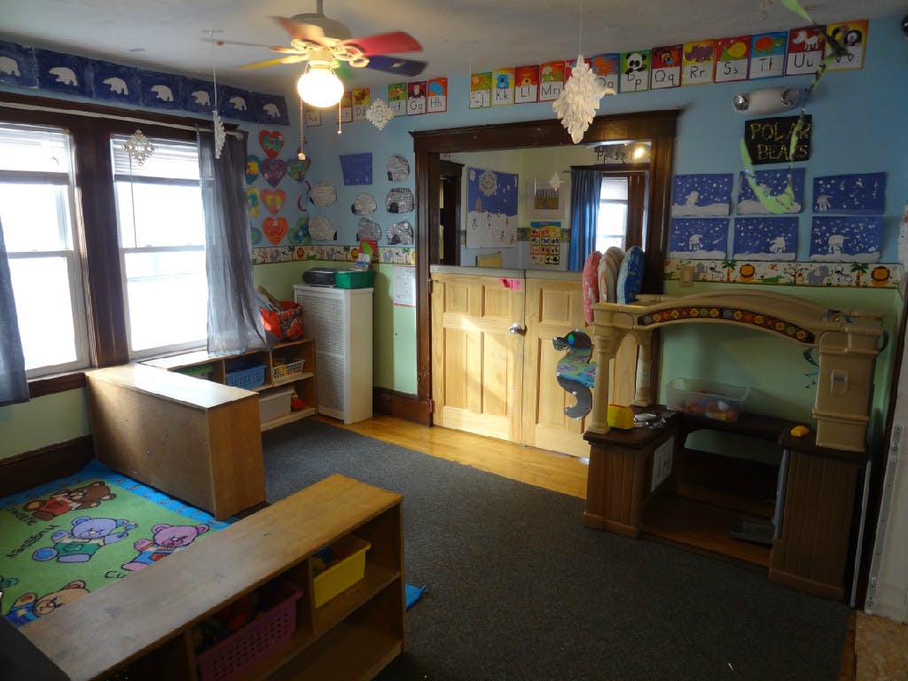 Playroom with colorful rug, windows, and wooden furniture