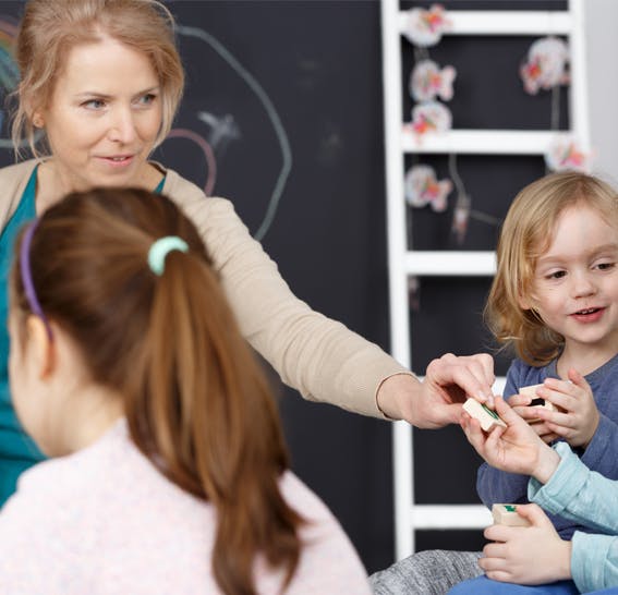 Adult person handing a small block to a child