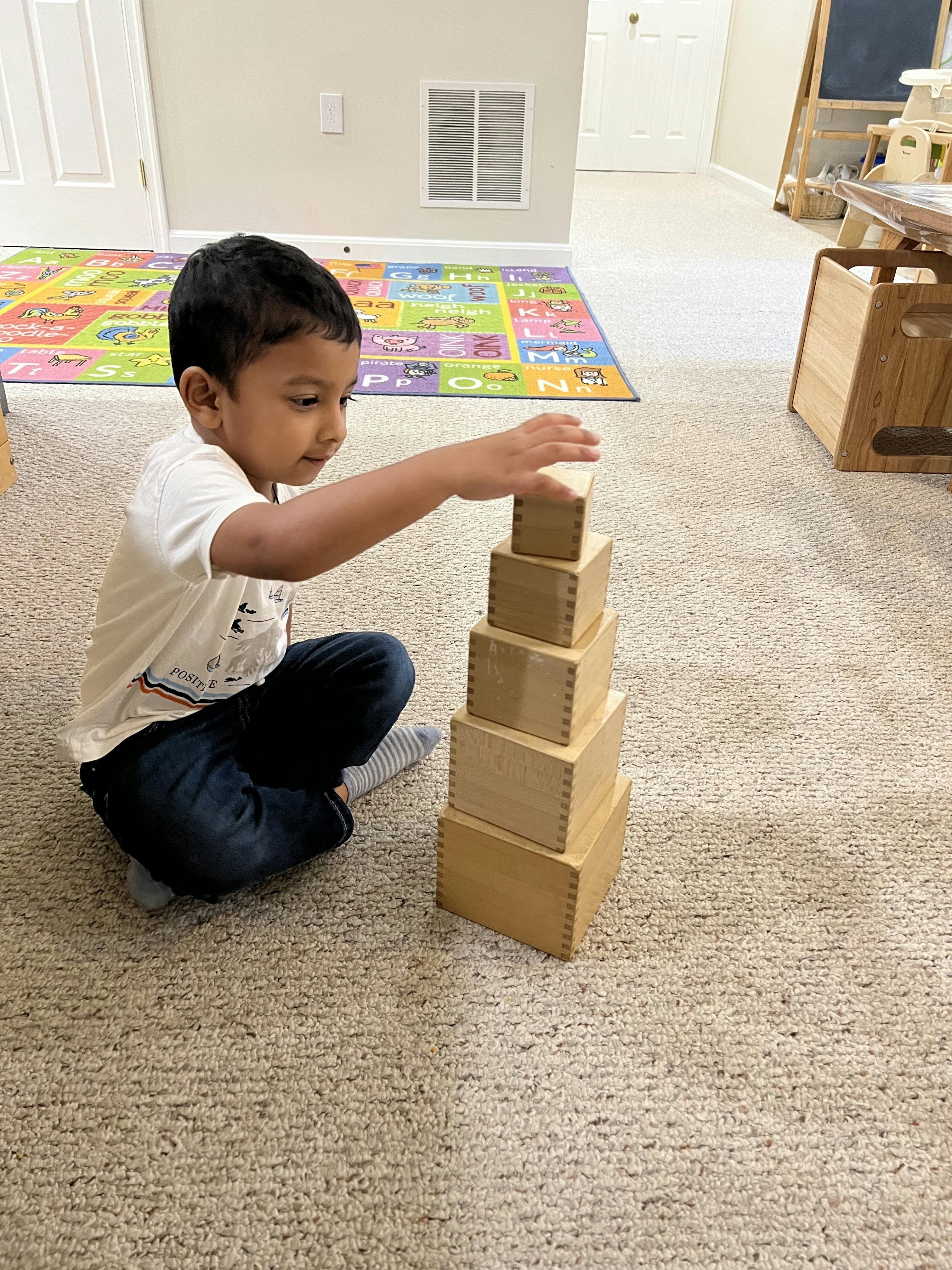 Child stacking wooden blocks on a carpeted floor