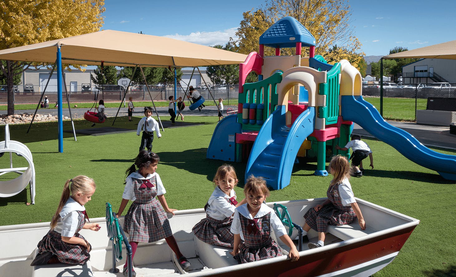 Children playing on a playground with a boat, slides, and swings