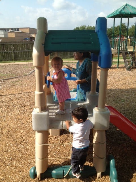 Two children and a person on a playground structure