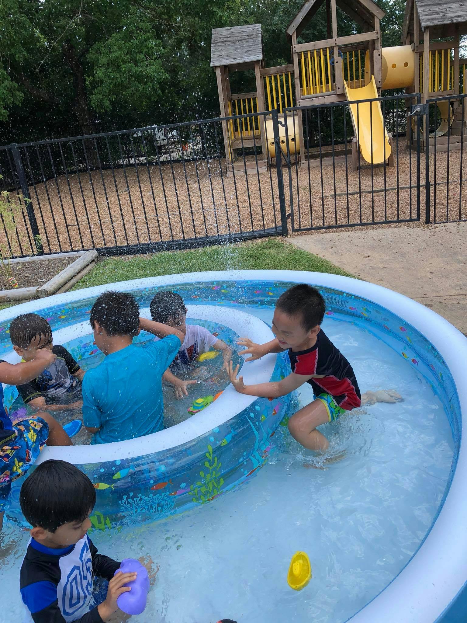Children playing in an inflatable pool with a playground in the background