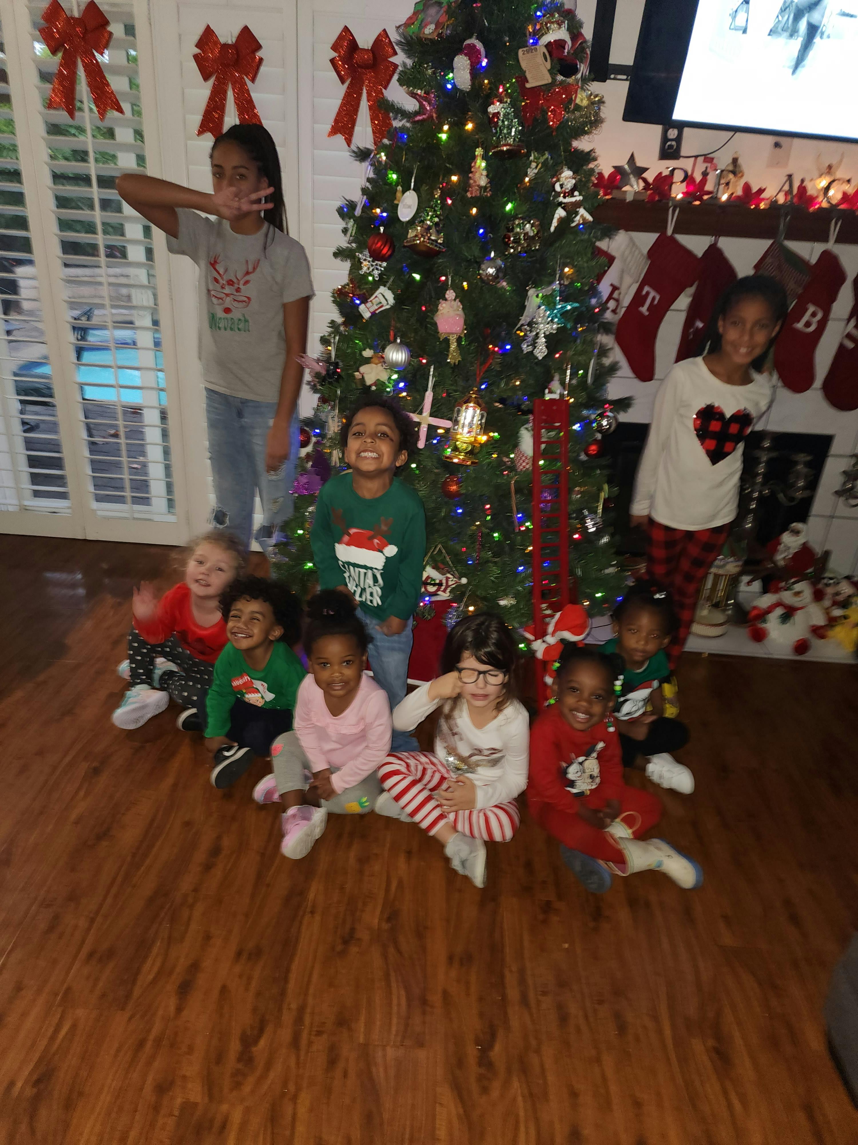 Group of children and teens posing around a Christmas tree