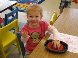 Child playing with modeling clay at a table