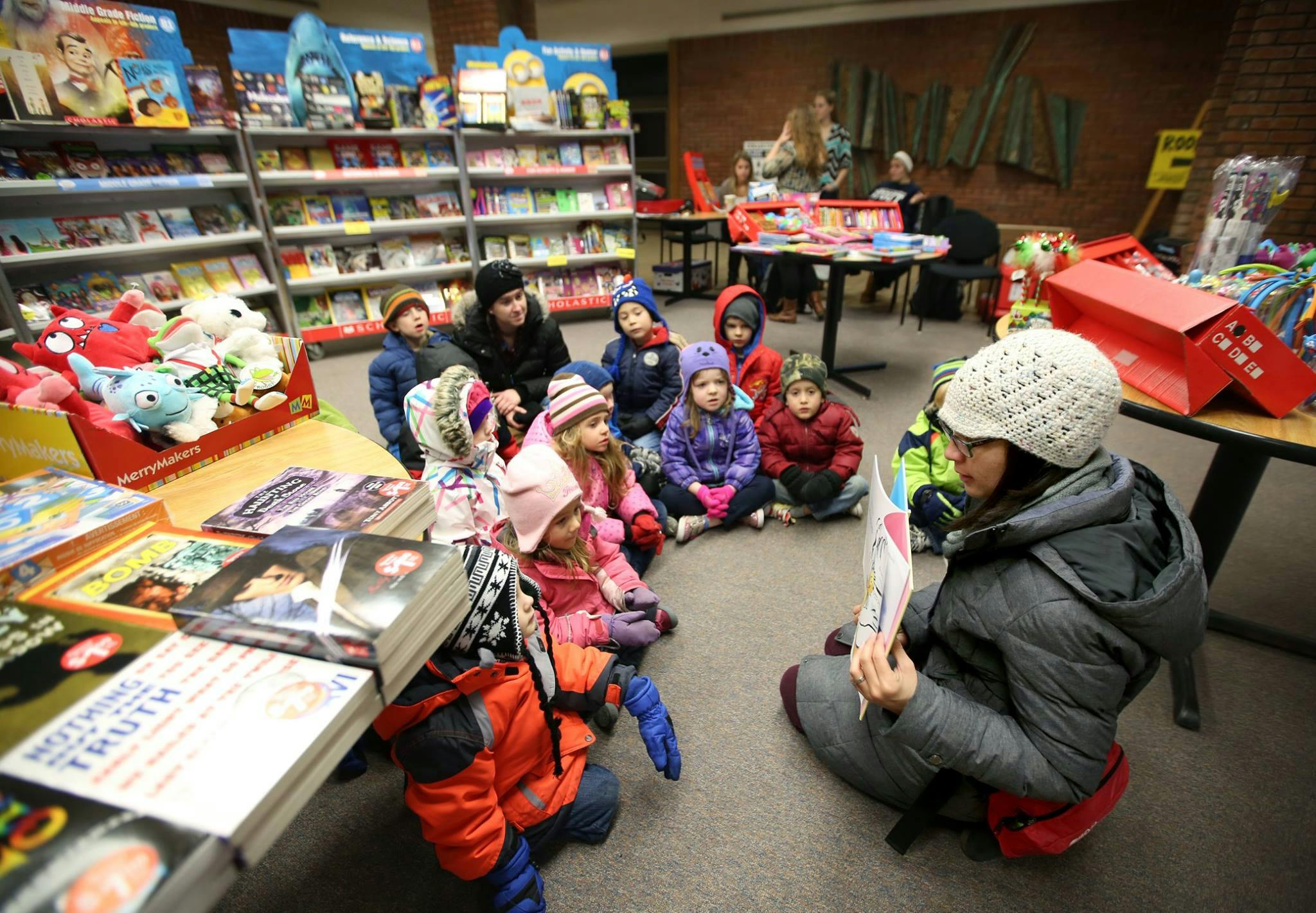 Person reading to a group of children sitting on the floor