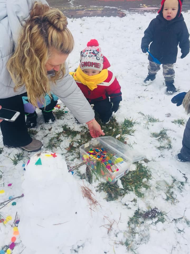 Person and child decorating a snowman with colorful shapes