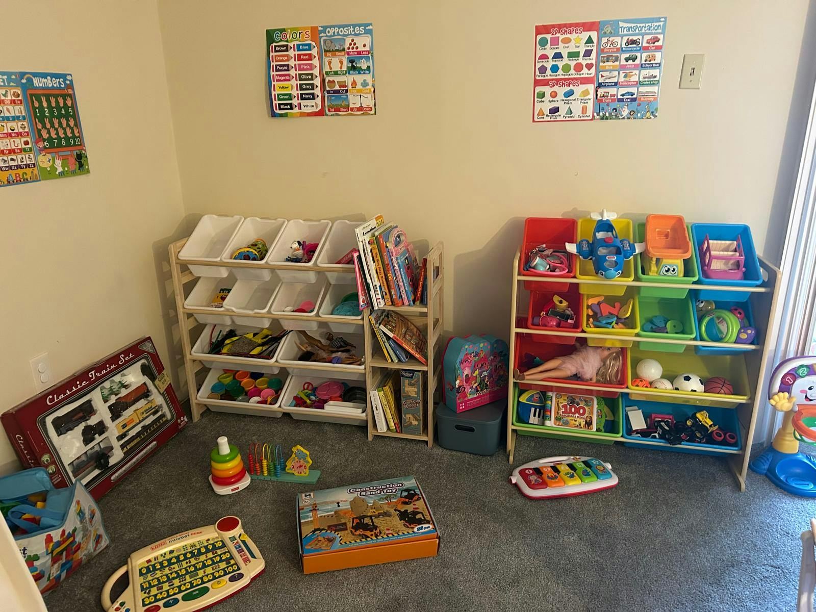 Playroom with two toy storage shelves, learning posters, and toys on the floor