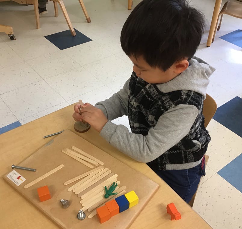 Child playing with craft sticks and blocks at a table